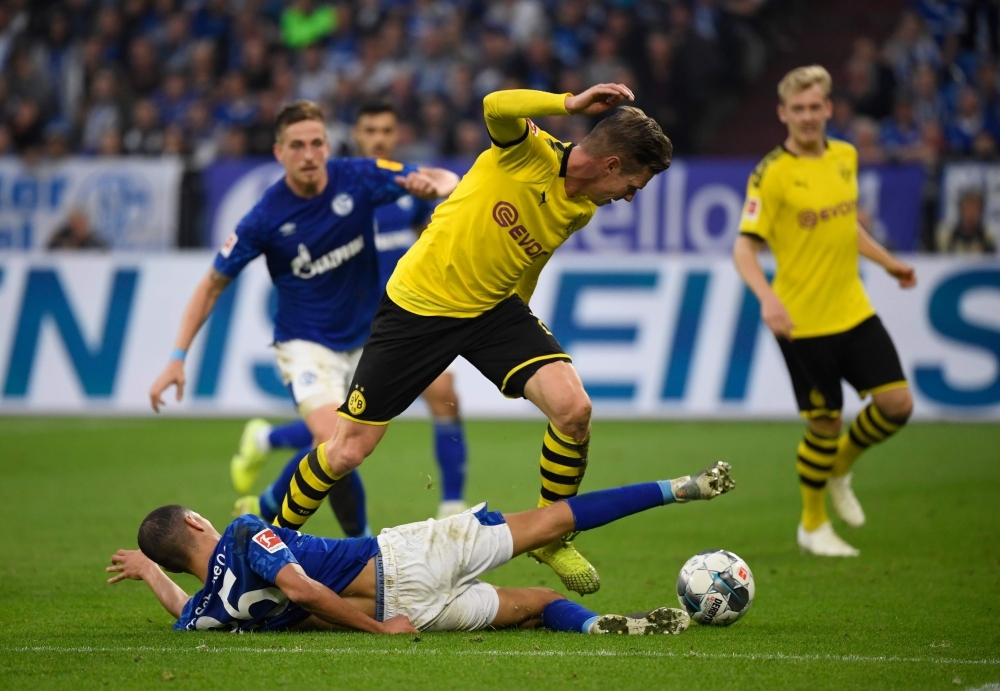 Schalke's French midfielder Amine Harit and Dortmund's Polish defender Lukasz Piszczek (R) vie for the ball during the German First division Bundesliga football match between Schalke 04 and Borussia Dortmund in Gelsenkirchen, on Saturday. — AFP