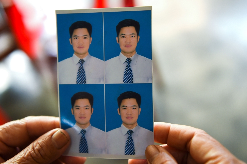 Pham Thi Lan, mother of 33-year old of Nguyen Van Hung who is feared to be among the 39 people found dead in a truck in Britain, hold his photographs at their house in Dien Chau district of Vietnam's Nghe An province on Monday. — AFP