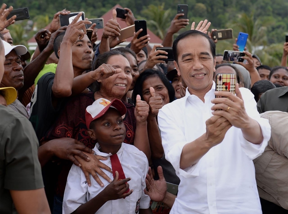 President Joko Widodo takes a selfie with Papuans welcoming him to Wamena, Papua, Indonesia, on Monday. — AFP