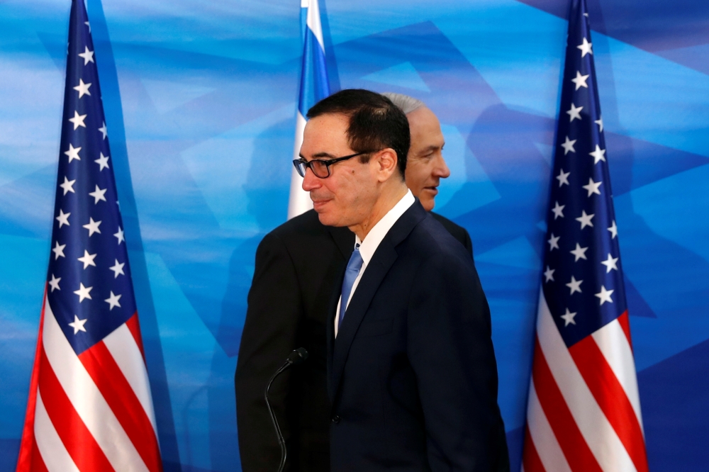 Israeli Prime Minister Benjamin Netanyahu walks behind US Treasury Secretary Steven Mnuchin as they prepare to deliver joint statements during their meeting in Jerusalem on Monday. — Reuters