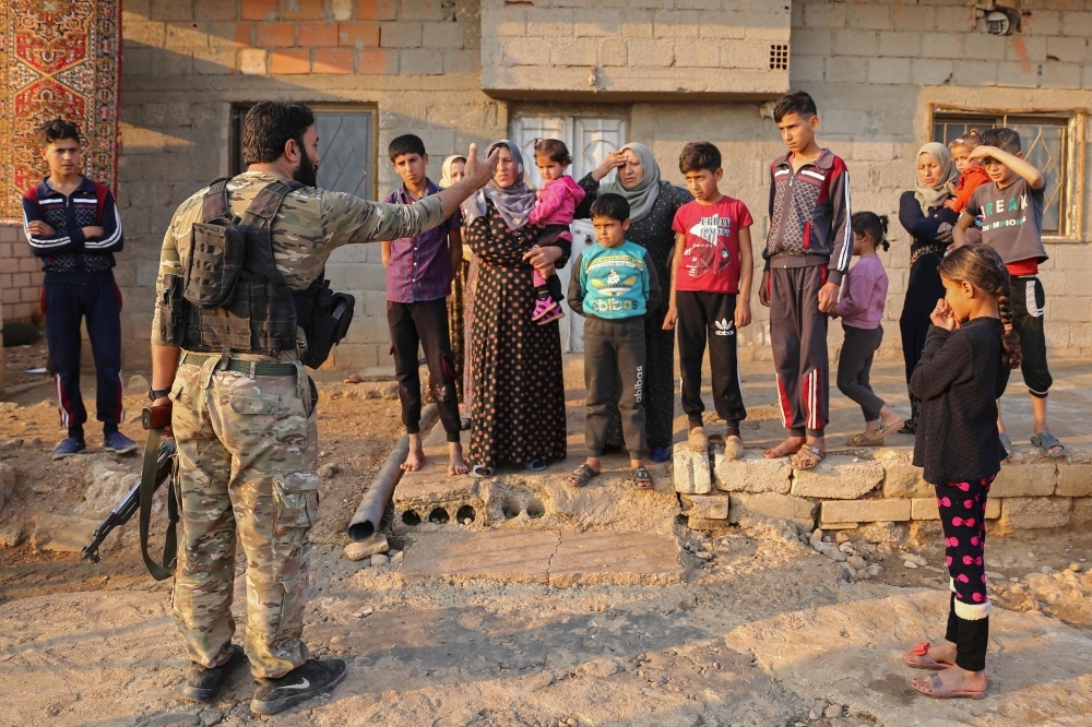Turkish-backed fighters question residents of Jan Tamr town, some 15 km east of Ras Al-Ain city near the Turkish-Syrian border, after they took over the town on Sunday. — AFP