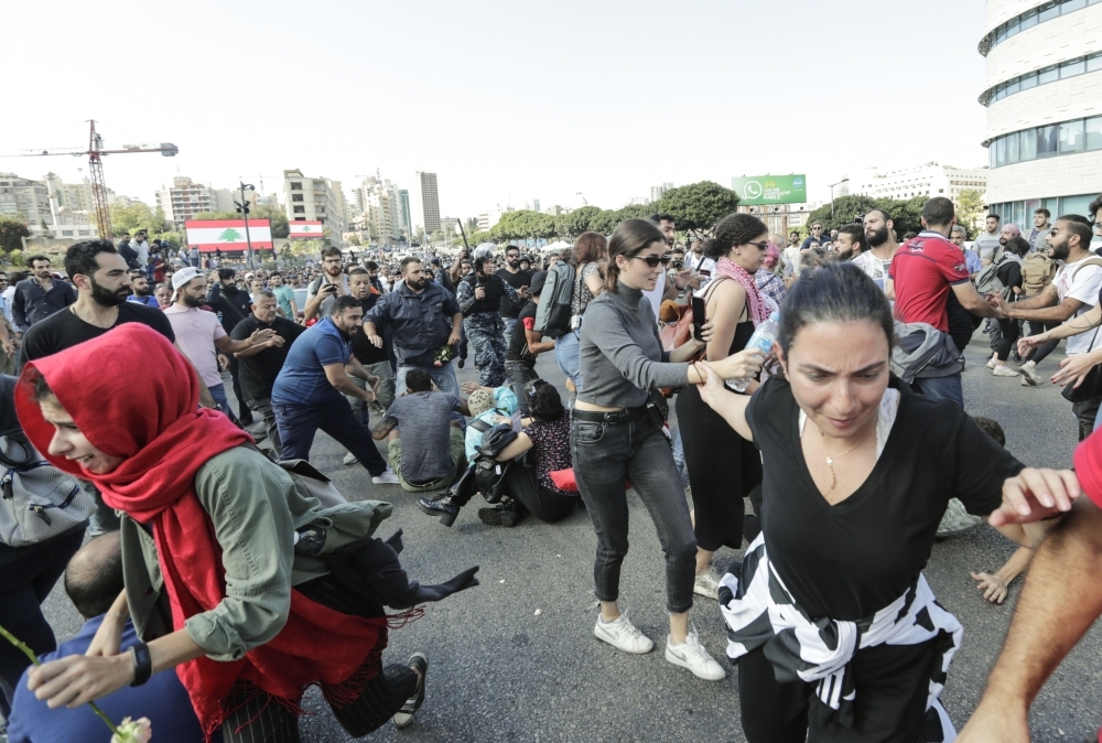 Lebanese protesters flee as others clash with supporters of the Shiite Hezbollah movement along a major bridge in the center of the capital Beirut during the 13th day of anti-government protests on Tuesday. — AFP