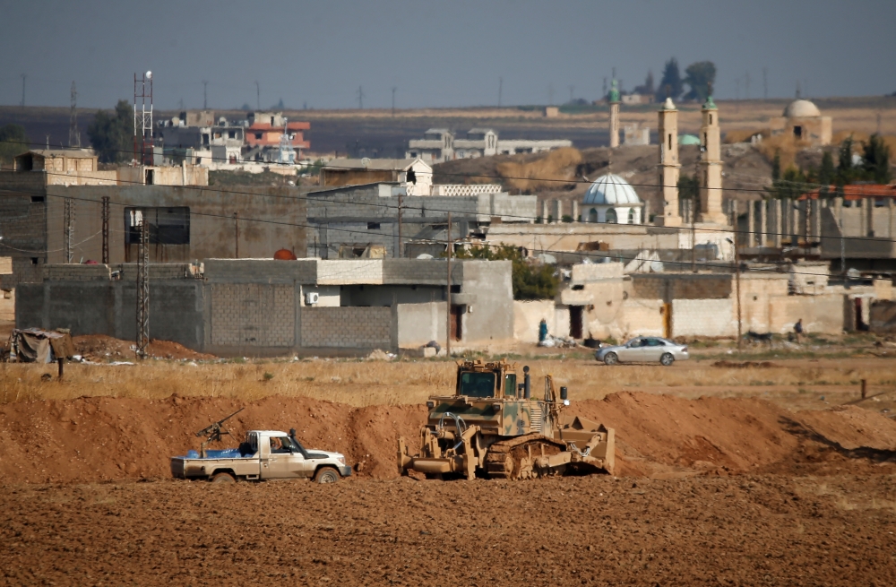 A vehicle belonging to Turkey-backed Syrian rebel fighters is parked next to a Turkish military bulldozer in the Syrian town of Ras Al-Ain, as seen from the Turkish border town of Ceylanpinar, in Sanliurfa province, Turkey, on Wednesday. — Reuters