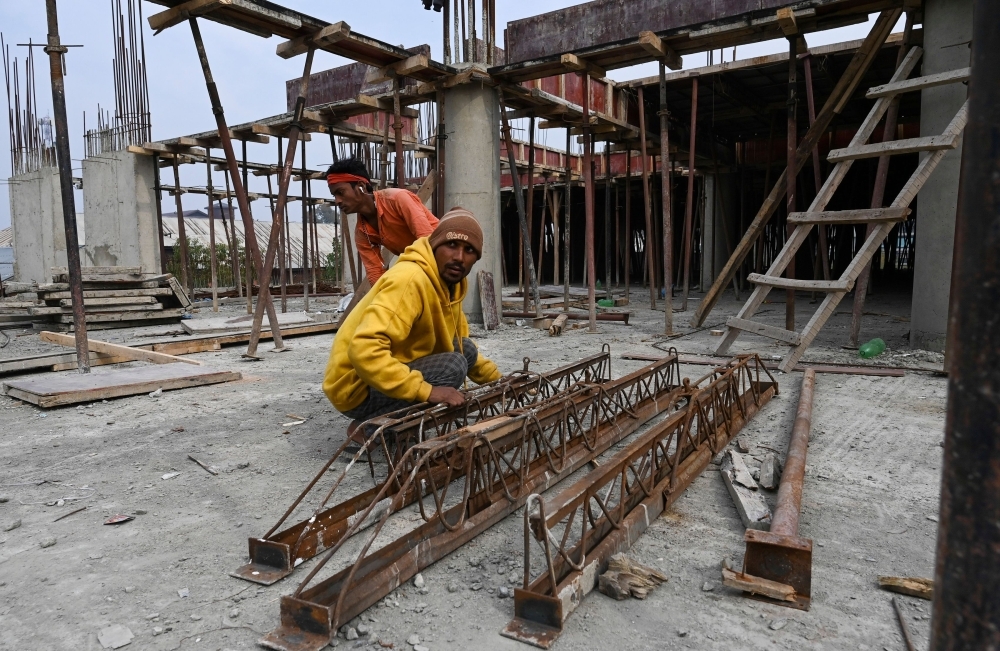 Migrant laborers work at a building construction site in Srinagar. — AFP