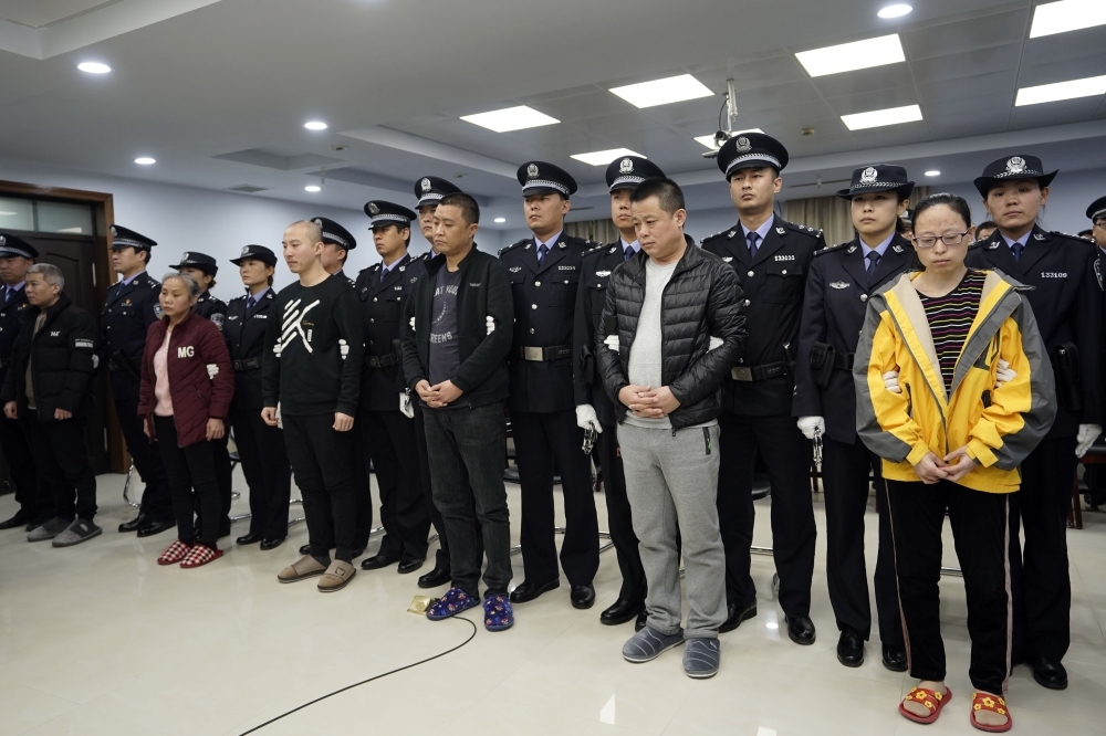This handout picture taken and released on Thursday by the Office of China National Narcotics Control Commission (ONNCC) shows defendants on drug charges standing with their handlers during a hearing at a court in Xintai in China's Hebei province. — AFP