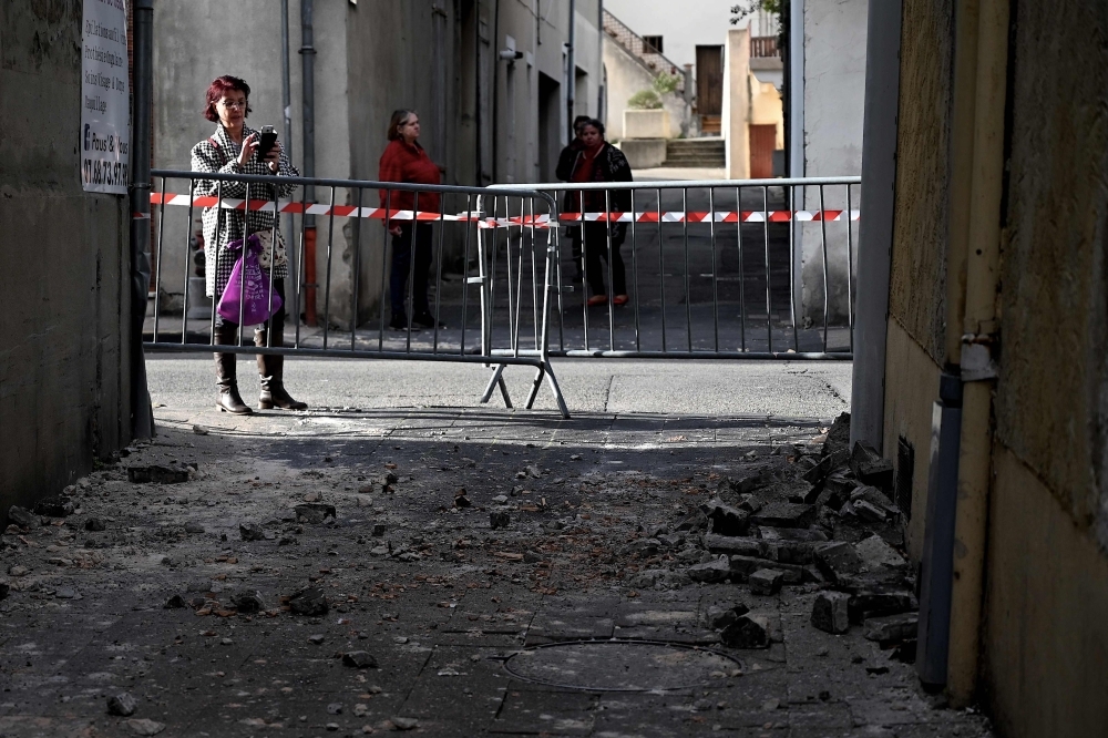 A woman takes a picture of bricks which fell from a wall in Le Teil, southeastern France, on Monday, after an earthquake with a magnitude of 5.4 hit the area.  — AFP