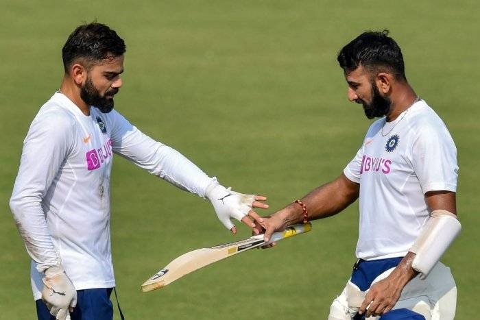 India's captain Virat Kohli (L) inspects teammate Cheteshwar Pujara's bat during a training session ahead of the first test match between India and Bangladesh at Holkar Cricket Stadium in Indore on Monday. — AFP