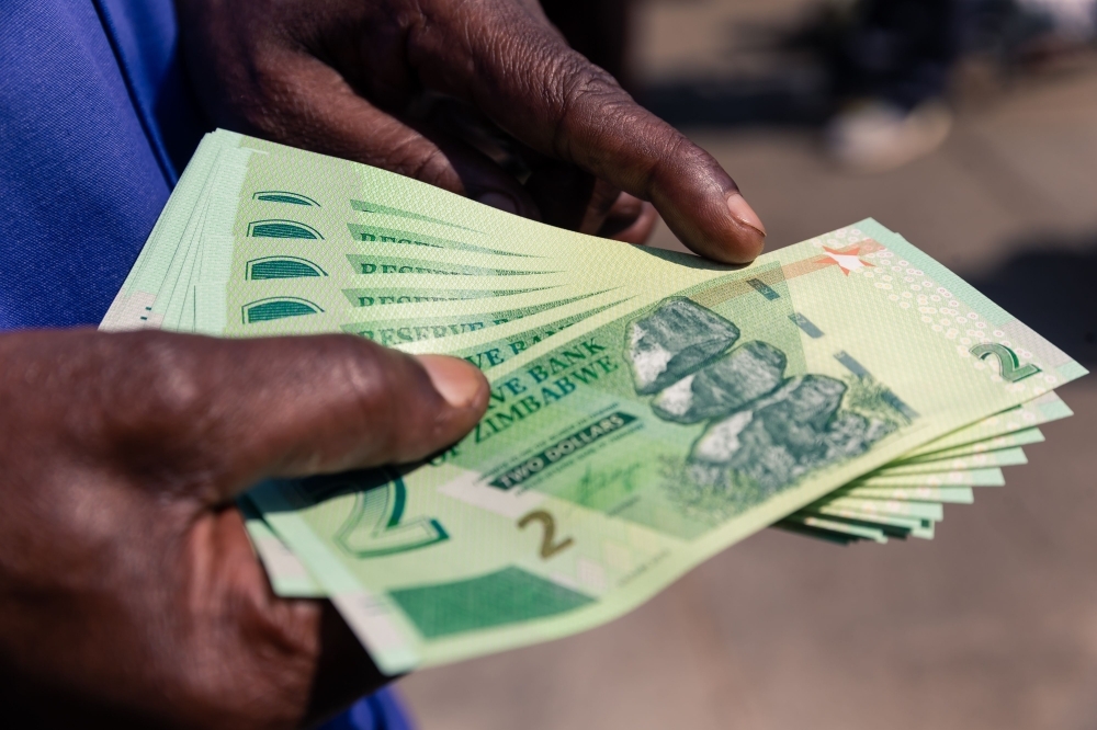 A man shows a wad of the new Zimbabwe two-dollar notes he received from a bank in Harare on Tuesday. — AFP