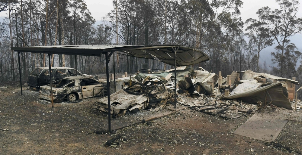 A fire truck hoses down embers after bushfires impacted houses and farmland near the small town of Glenreagh, some 600kms north of Sydney, on Wednesday. -AFP 