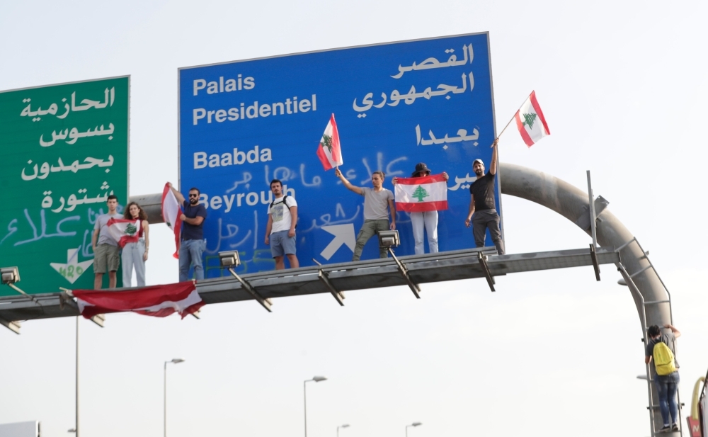 Lebanese demonstrators stand on a traffic sign on the road leading to the Presidential Palace in Baabda, on the eastern outskirts of Beirut, on Wednesday. — AFP