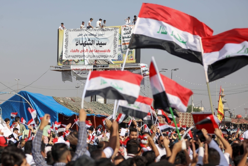 Iraqi protesters chant slogans and wave their country's national flags during ongoing anti-government demonstrations in the southern city of Basra, on Wednesday. — AFP