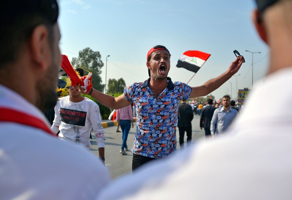 Iraqi protesters chant slogans and wave their country's national flags during ongoing anti-government demonstrations in the southern city of Basra, on Wednesday. — AFP