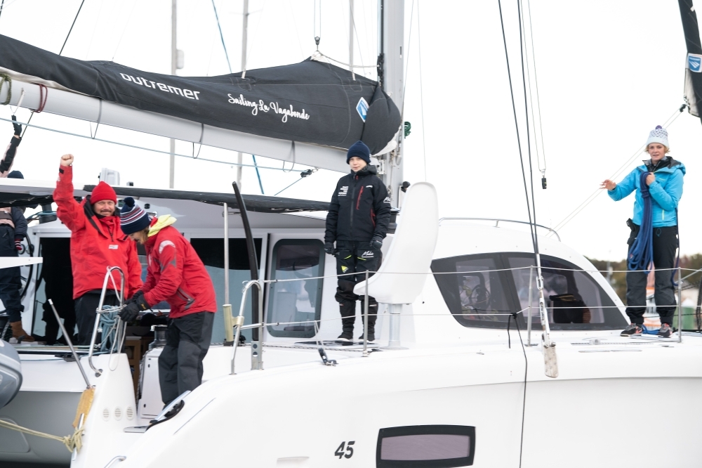 Swedish climate activist Greta Thunberg, center, stands aboard the catamaran La Vagabonde with her father Svante Thunberg, left, La Vagabonde owner Riley Whitelum, second left, and sailor Nikki Henderson, right, as they set sail to Europe in Hampton, Virginia, on Wednesday. — AFP