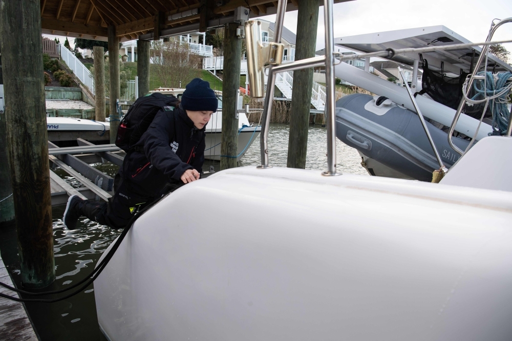 Swedish climate activist Greta Thunberg, center, stands aboard the catamaran La Vagabonde with her father Svante Thunberg, left, La Vagabonde owner Riley Whitelum, second left, and sailor Nikki Henderson, right, as they set sail to Europe in Hampton, Virginia, on Wednesday. — AFP