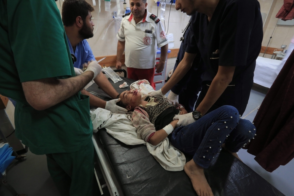 Palestinian medical workers tend to wounded children, members of a family where six were killed in an Israeli air strike, in central Gaza Strip's Deir Al-Balah on Thursday. — AFP