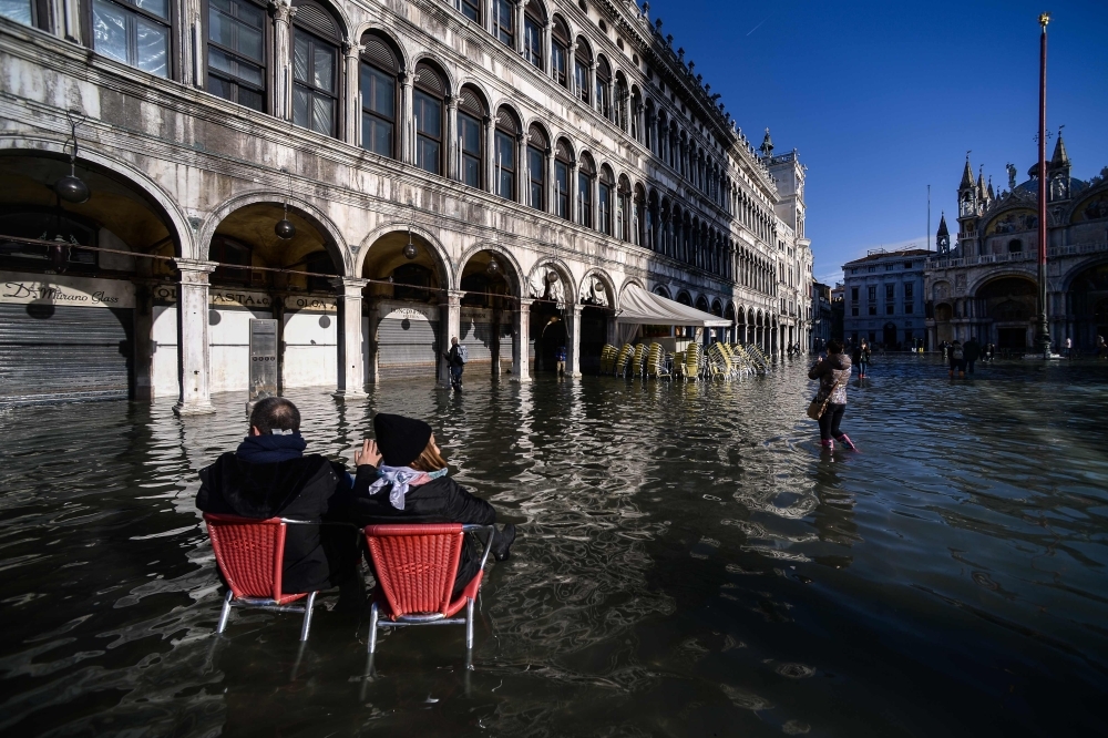 People walk on a footbridge across the flooded St. Mark's Square by St. Mark's Basilica, rear, and the Doge's palace, right, in Venice, Italy, on Thursday. — AFP