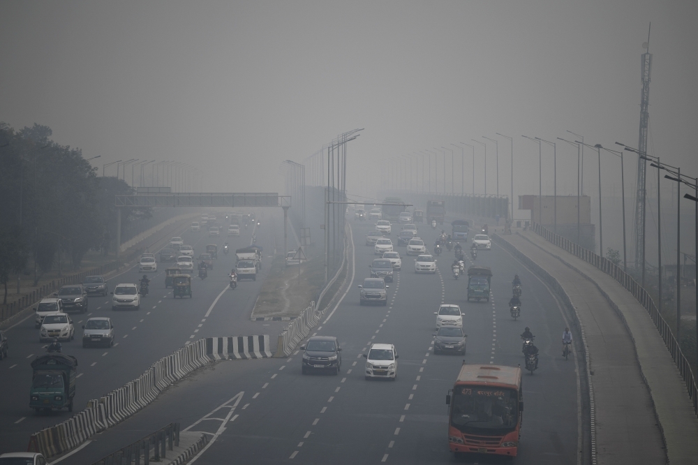 Commuters drive along a motorway under heavy smog conditions in New Delhi on Thursday. — AFP