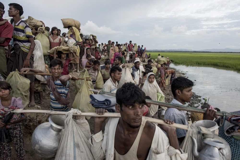 Rohingya refugees carry a woman over a shallow canal after crossing the Naf River as they flee violence in Myanmar to reach Bangladesh in Palongkhali near Ukhia in this Oct. 16, 2017 file photo. — AFP