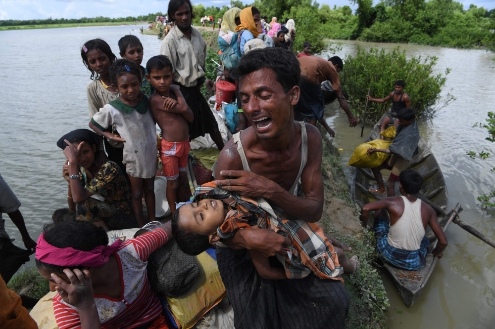 Rohingya refugees carry a woman over a shallow canal after crossing the Naf River as they flee violence in Myanmar to reach Bangladesh in Palongkhali near Ukhia in this Oct. 16, 2017 file photo. — AFP