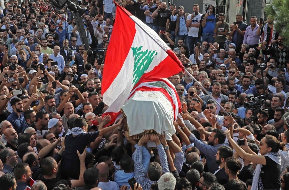 The coffin of slain Lebanese protester Alaa Abu Fakhr, draped in a national flag, is carried  by mourners through the streets of his hometown of Chouaifet, southeast of Beirut, during his funeral procession on Thursday. — AFP