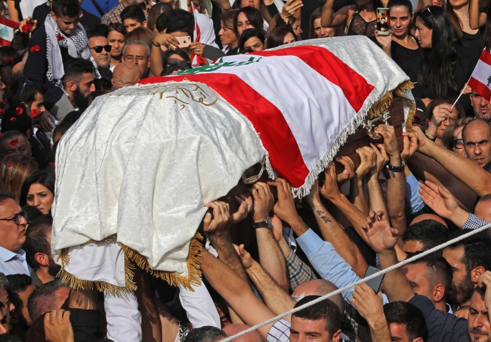 The coffin of slain Lebanese protester Alaa Abu Fakhr, draped in a national flag, is carried  by mourners through the streets of his hometown of Chouaifet, southeast of Beirut, during his funeral procession on Thursday. — AFP