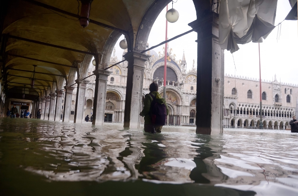 A person walks across a flooded arcade by St. Mark's Basilica on Friday in Venice, two days after the city suffered its highest tide in 50 years. Flood-hit Venice was bracing for another exceptional high tide as Italy declared a state of emergency for the UNESCO city where perilous deluges have caused millions of euros worth of damage. — AFP