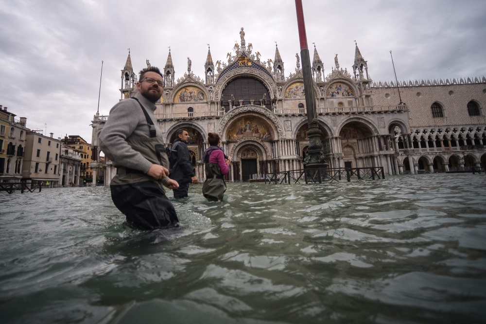 People walk across the flooded St. Mark's Square, by St. Mark's Basilica on Friday in Venice, two days after the city suffered its highest tide in 50 years. — AFP