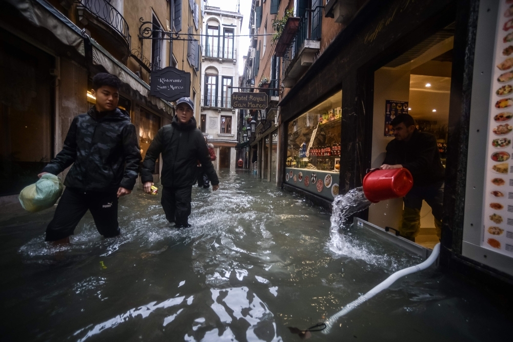 People walk across the flooded St. Mark's Square, by St. Mark's Basilica on Friday in Venice, two days after the city suffered its highest tide in 50 years. — AFP