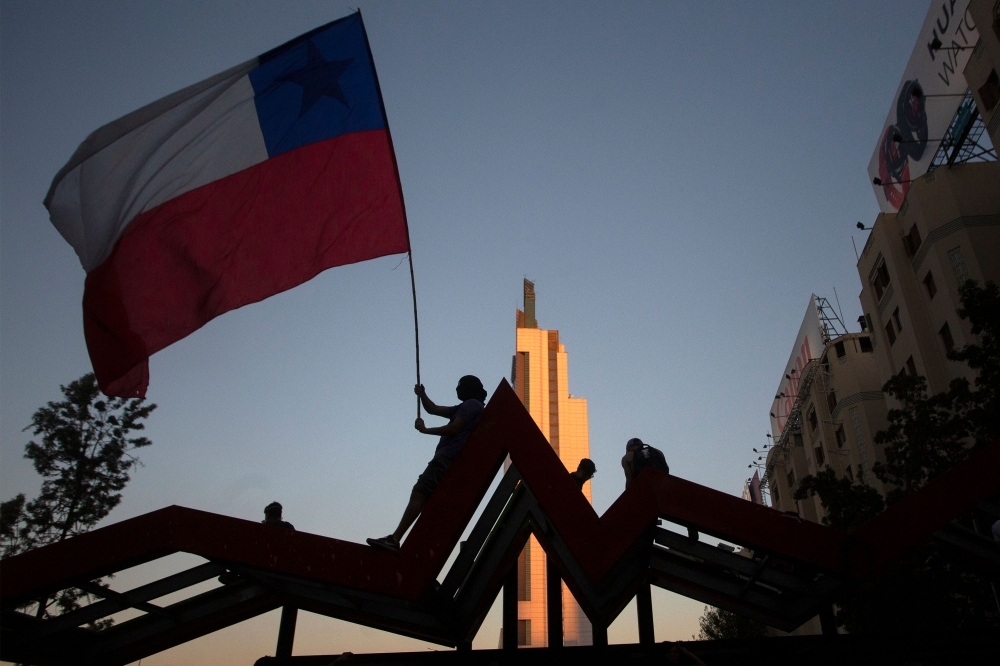 A demonstrator flutters a Chilean national flag during a protest against the government in Santiago on Friday. — AFP