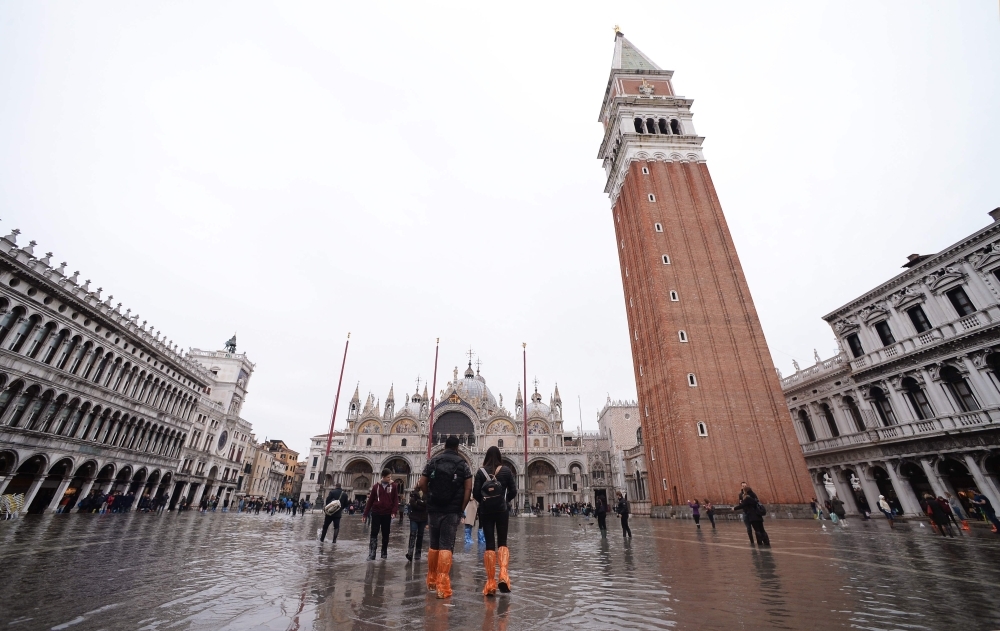 Tourists walks in St. Mark square on Saturday in Venice, three days after the city suffered the highest tide in 50 years. -AFP