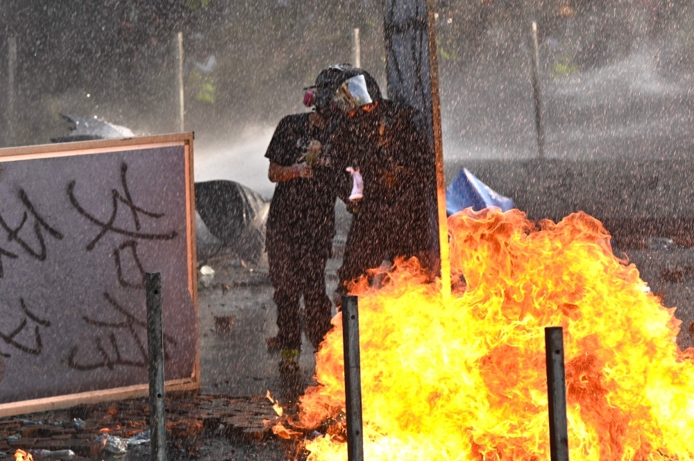 Protesters throw Molotov cocktails at the police who use water canon outside the Hong Kong Polytechnic University in Hong Kong on Sunday. -AFP