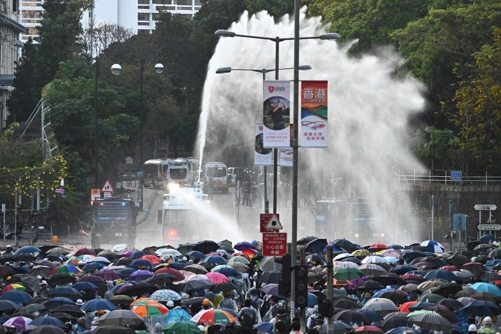 Protesters throw Molotov cocktails at the police who use water canon outside the Hong Kong Polytechnic University in Hong Kong on Sunday. -AFP