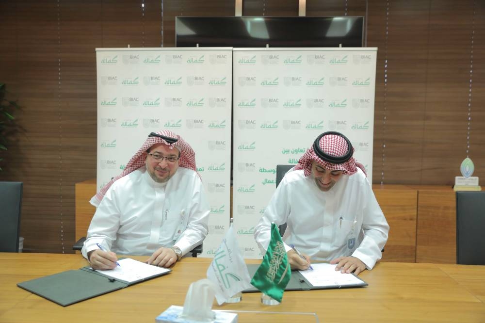 Homam Hashem, General Manager of Kafalah Program; and Nawaf Al Sahhaf, the CEO of BIAC, sign the agreement