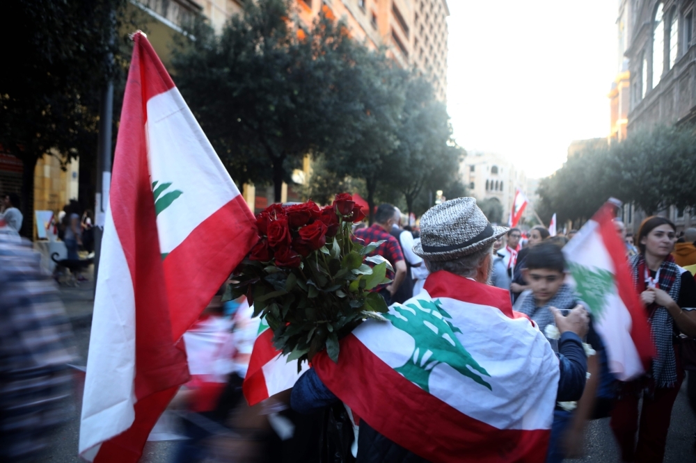 A street vendor sells roses and Lebanese flags to anti-government protesters during a demonstration in downtown Beirut on Sunday. -AFP