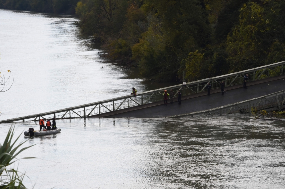 Rescuers sail near a suspension bridge which collapsed in Mirepoix-sur-Tarn, near Toulouse, southwest France, on Monday. — AFP