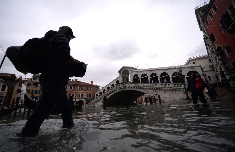 Visitors walk at the sunset in the flooded street in Venice, during 