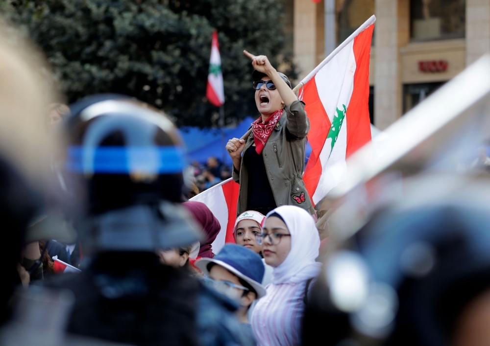 A Lebanese protester holds a national flag as she chants slogans during a demonstration at Riad Al-Solh square near the government palace and the parliament headquarters in the capital Beirut's downtown district on Tuesday. — AFP