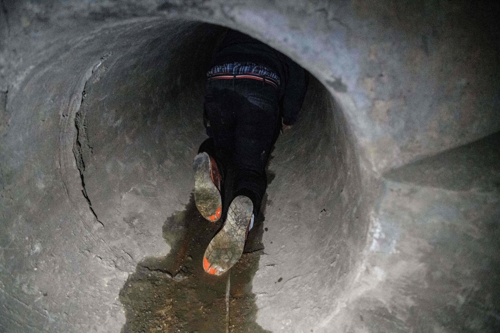 A protester crawls within a sewer tunnel to see how wide it is as he and others try to find an escape route from the Hong Kong Polytechnic University in the Hung Hom district of Hong Kong early morning on Tuesday. — AFP