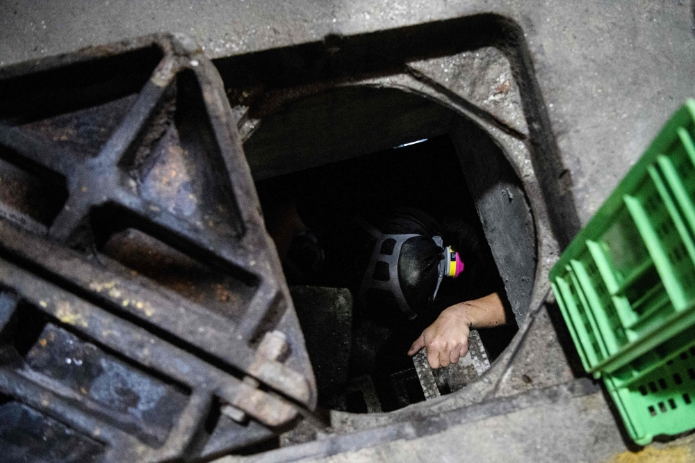 A protester crawls within a sewer tunnel to see how wide it is as he and others try to find an escape route from the Hong Kong Polytechnic University in the Hung Hom district of Hong Kong early morning on Tuesday. — AFP