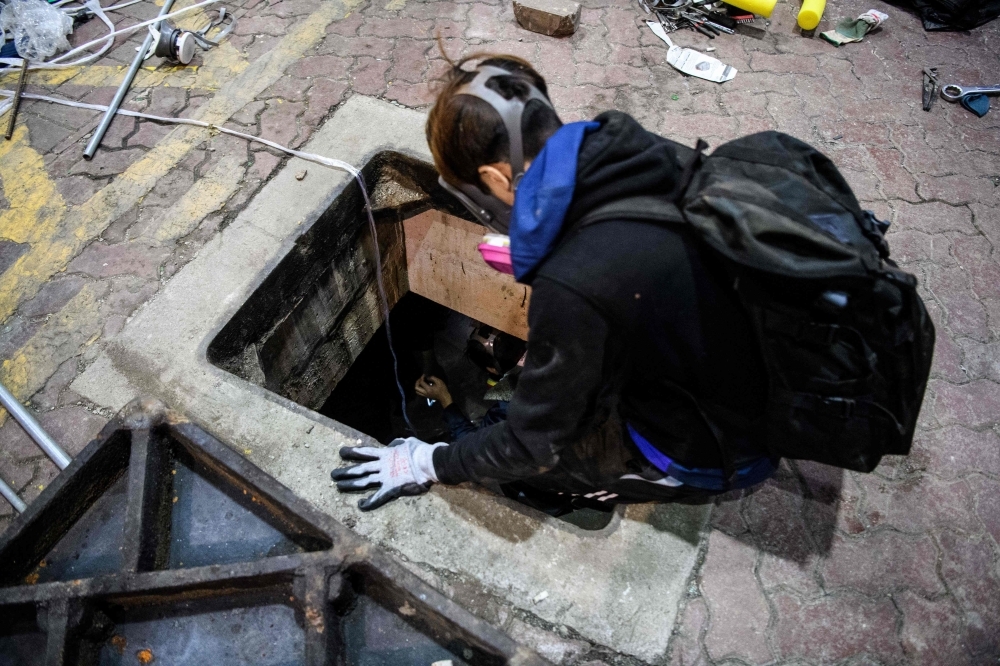 A protester crawls within a sewer tunnel to see how wide it is as he and others try to find an escape route from the Hong Kong Polytechnic University in the Hung Hom district of Hong Kong early morning on Tuesday. — AFP