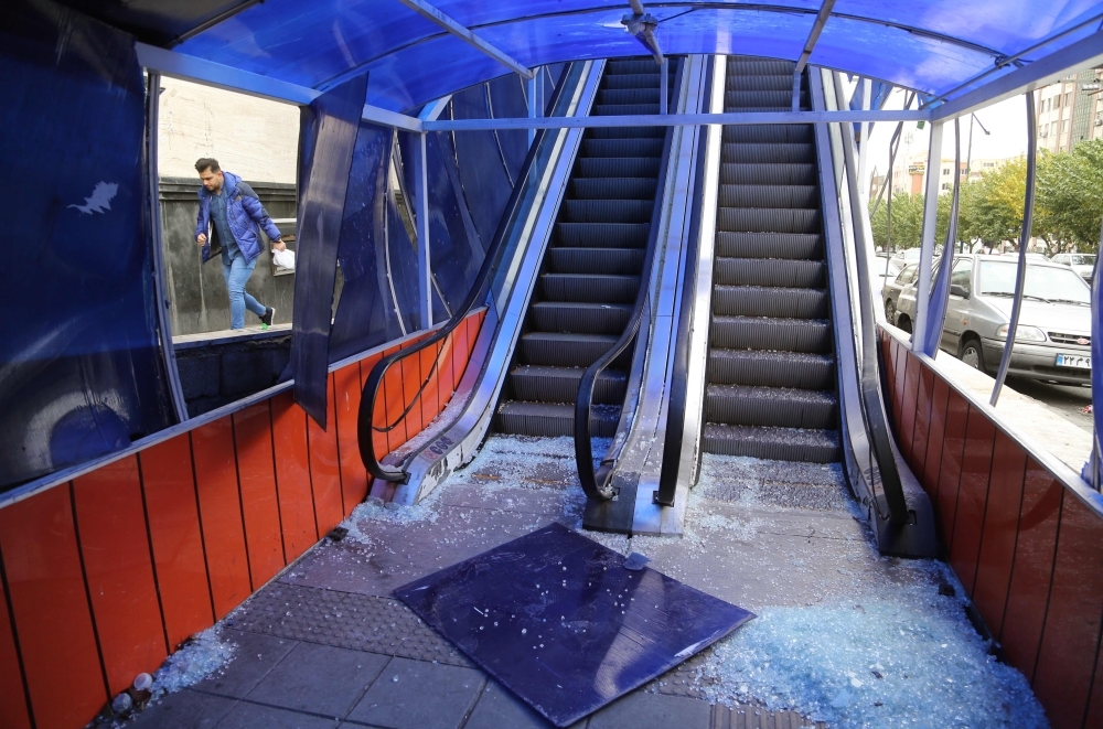 An Iranian man walks past a the entrance of a pedestrian overpass that was vandalized by protesters in Tehran on Tuesday. — AFP