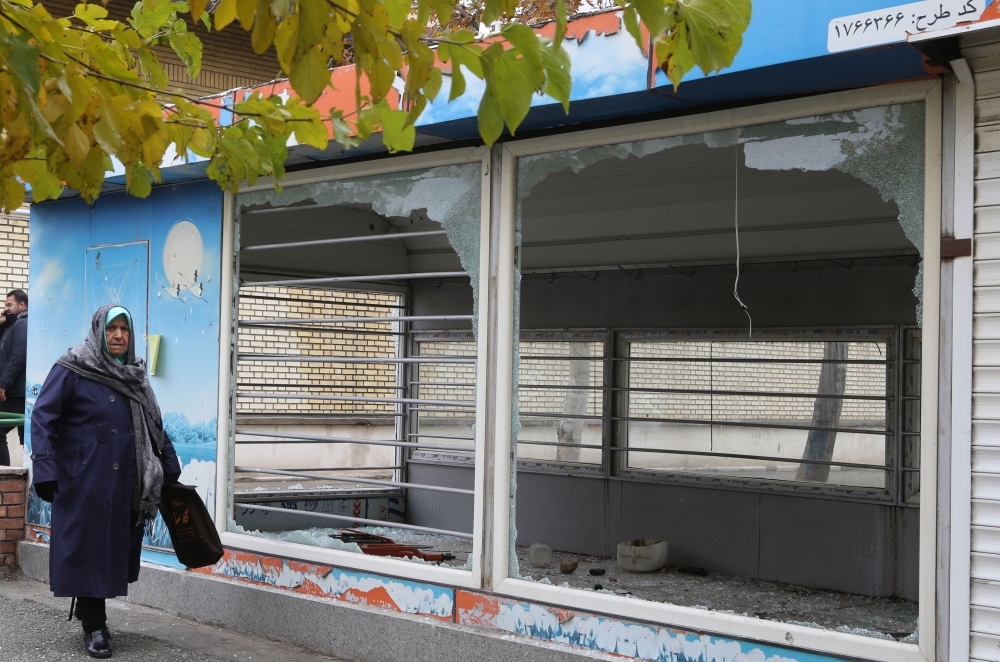 An Iranian man walks past a the entrance of a pedestrian overpass that was vandalized by protesters in Tehran on Tuesday. — AFP