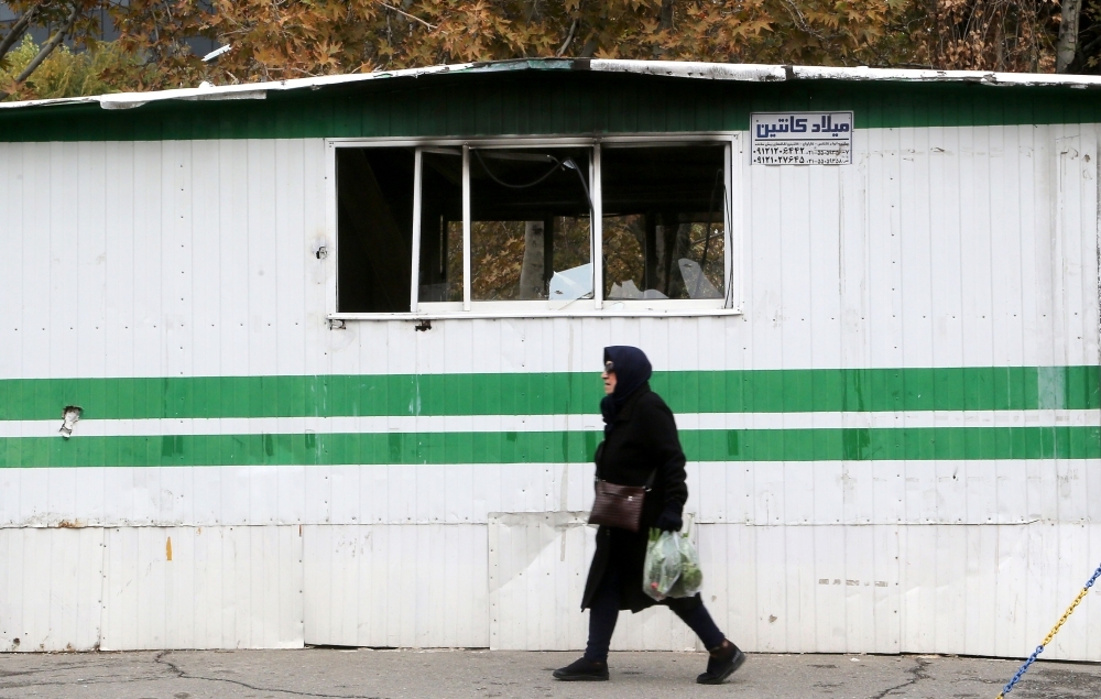 An Iranian man walks past a the entrance of a pedestrian overpass that was vandalized by protesters in Tehran on Tuesday. — AFP