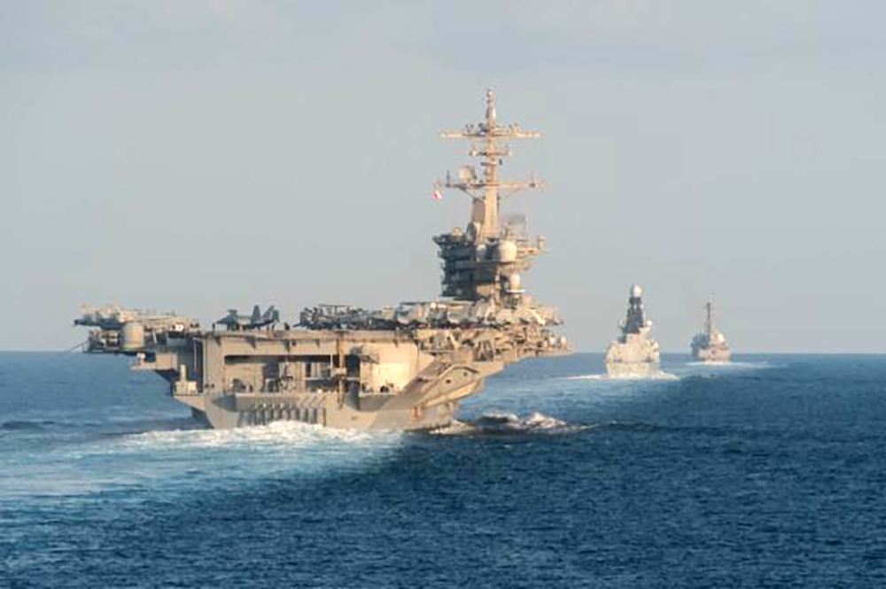 The aircraft carrier USS Abraham Lincoln, the air-defense destroyer HMS Defender and the guided-missile destroyer USS Farragut transit the Strait of Hormuz on Tuesday. -AFP