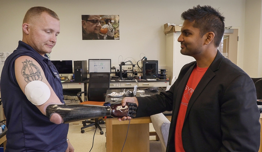 This undated handout photo released by the Northwestern University on Wednesday shows retired US Army Sergeant Garrett Anderson, left, shaking hands with his prosthetic arm while wearing Northwestern University’s wireless patch, a new second-skin 