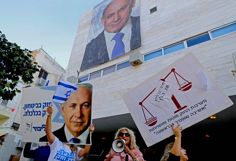 Supporters of Israel's Labour party chant slogans and hold flags and banners as they attend a rally against Israeli Prime Minister Benjamin Netanyahu outside the Likud party headquaters in the coastal Mediterranean city of Tel Aviv on Friday. — AFP