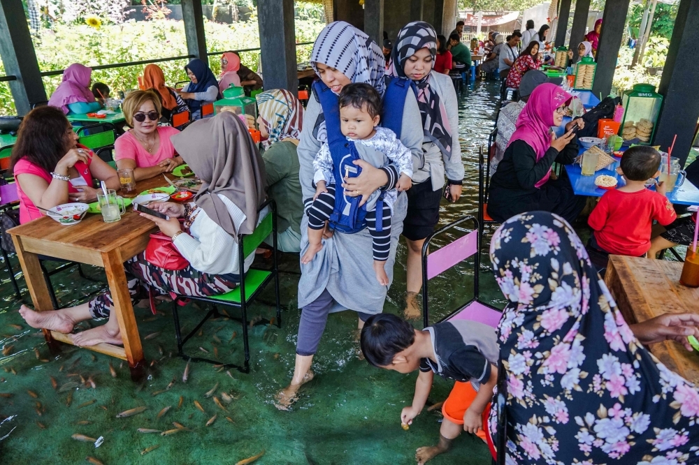 Fish nibble at the feet of Indonesian diners as they have their lunch at a fish pool restaurant at Wedomartani village in Yogyakarta, Indonesia, in this Nov. 15, 2019 file photo. — AFP