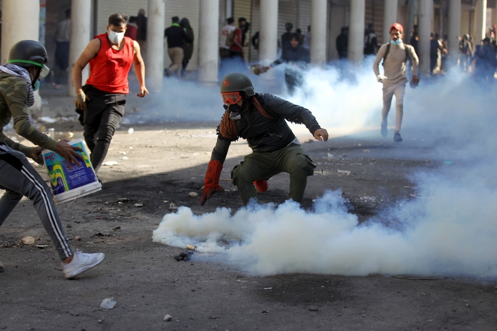 Iraqi anti-government protesters clash with security forces in Al-Rasheed street near Al-Ahrar bridge on Friday. — AFP