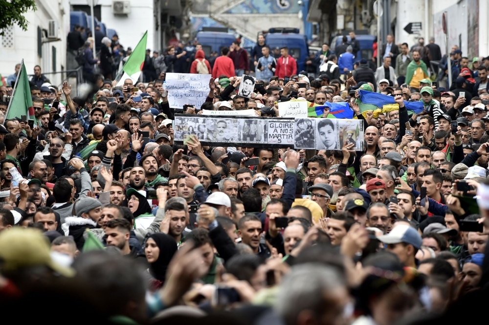 Algerian protesters lift banners as they take part in an anti-government demonstration in the center of the capital Algiers on Friday. — AFP