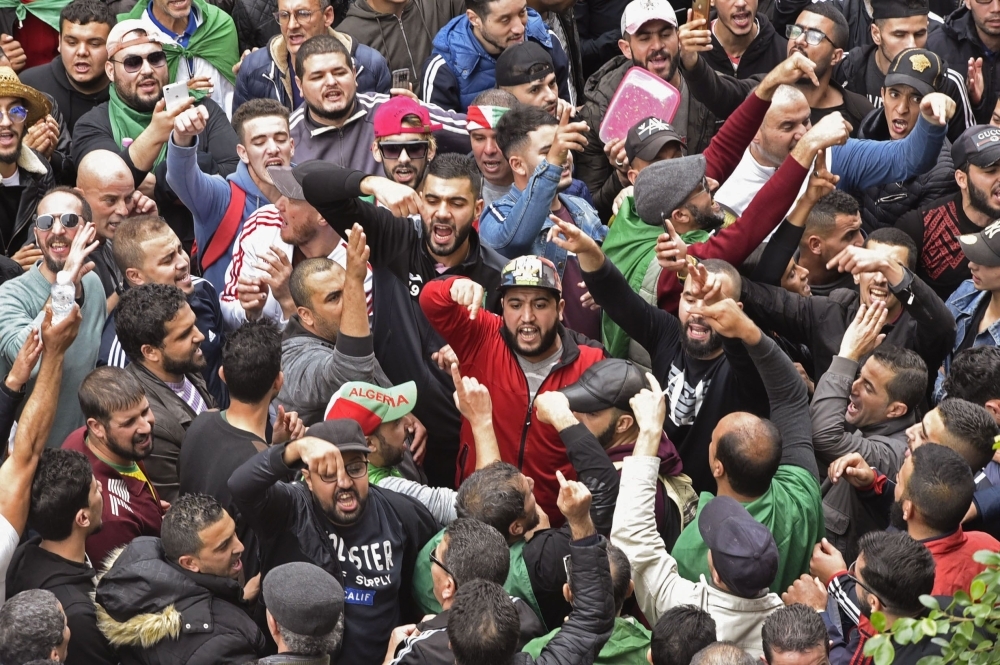 Algerian protesters lift banners as they take part in an anti-government demonstration in the center of the capital Algiers on Friday. — AFP